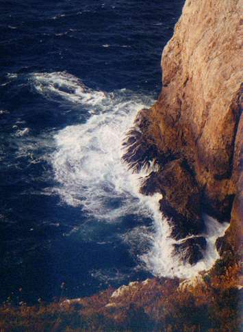 Ein Wellen-umtoster Abschnitt der Felsküste beim Leuchturm in Sagres.